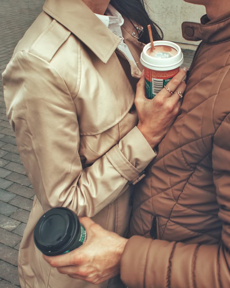 Deux personnes en manteau, serrées l'une contre l'autre, un café à la main