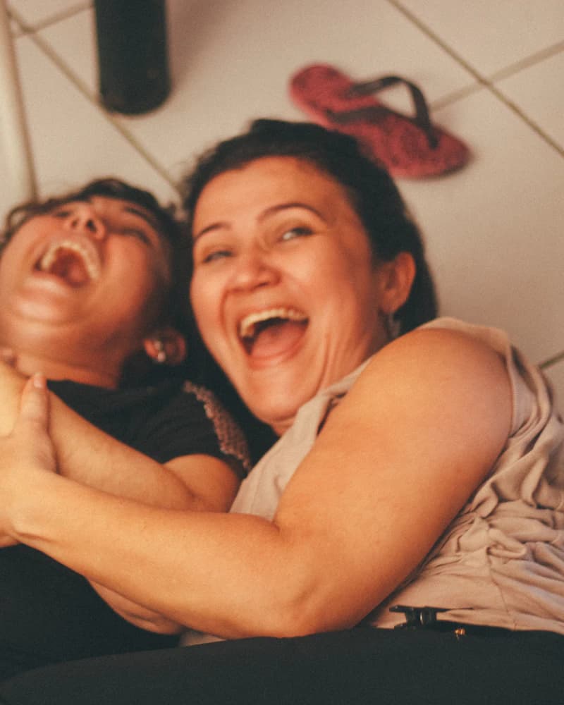 Deux femmes qui éclatent de rire, serrées l'une contre l'autre
